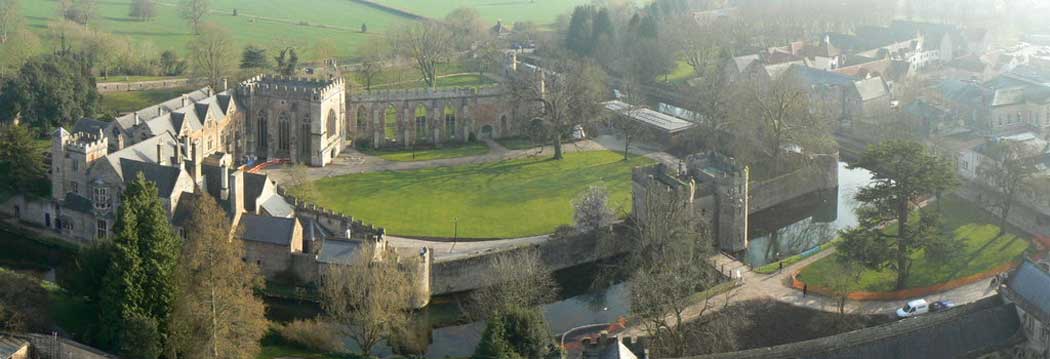 An aerial view of the Bishop's Palace in Wells showing the moat, the gatehouse (bottom right), the remaining walls of the great hall (top), the palace and the chapel (left) and the current bishop's residence (bottom left). (Photo: Edwin Graham [CC BY-SA 2.0])